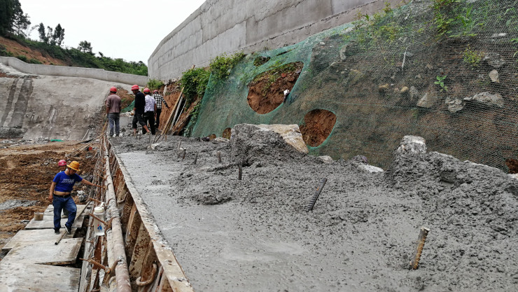 图为工人们正在进行挡土墙施工,用石头和混凝土,加固边坡墙.