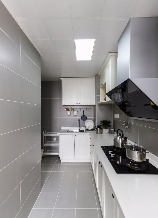 厨房空间不大,地面与墙面通铺灰色哑光砖,白色美缝更显层次,搭配l