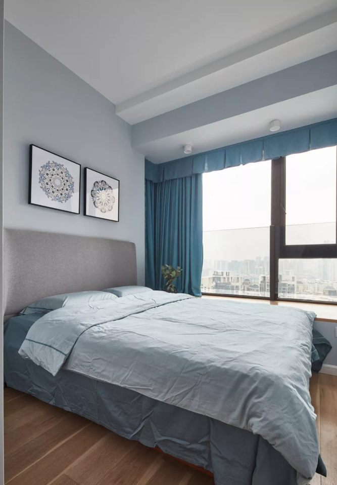 灰色布艺床搭配蓝灰色背景,装饰两幅简框画点缀,蓝色窗帘与床品呼应